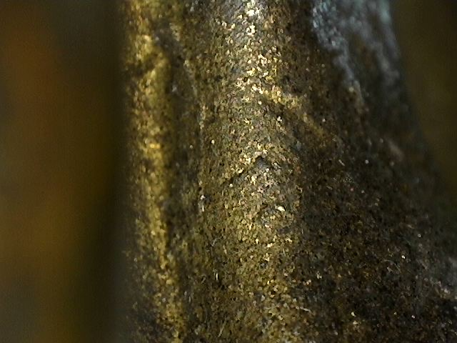Microscopic detail of oxidation with cuprite and malachite on a bronze Buddha statue