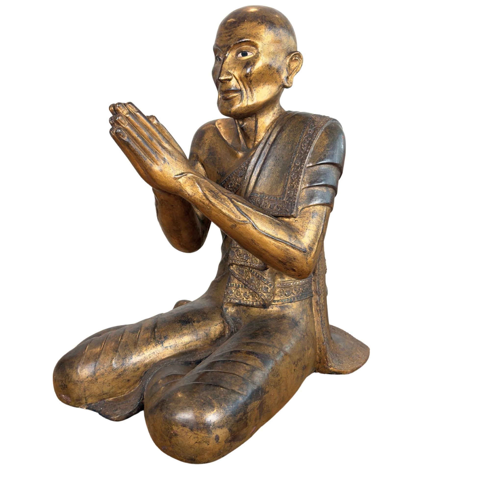 Burmese monk Moggallana of gilded wood kneeling in devotion with inlaid glass eye and deep lacquer patina.