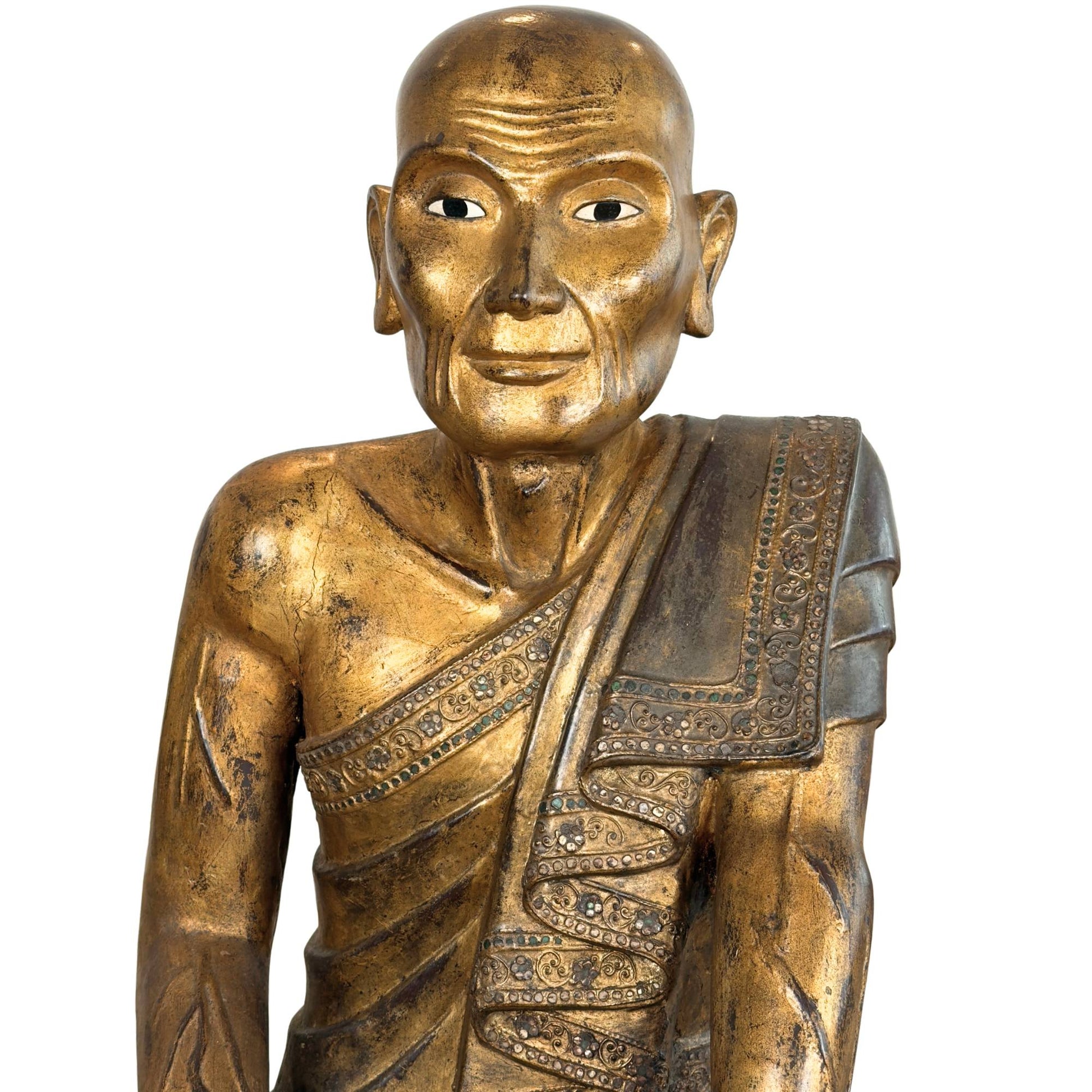 Face of the Burmese wooden statue of chief disciple Sariputta with hand-carved wrinkles and weathered gold leaf.