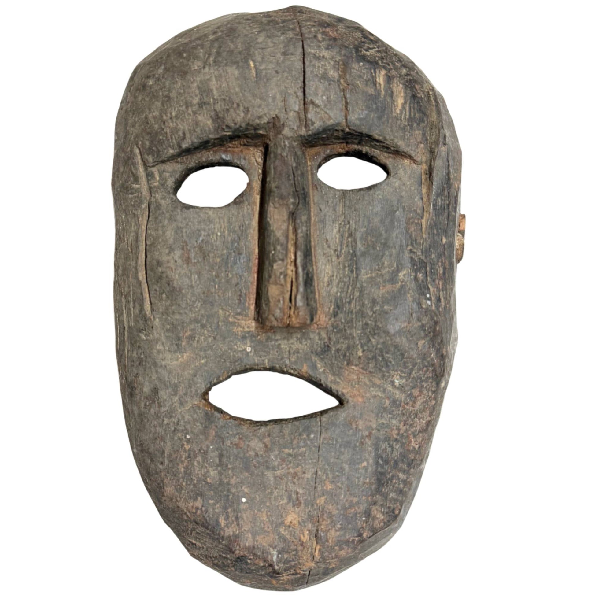 Authentic antique wooden shaman mask from the Himalayan region, primitively hand-carved with a deep patina of wear.
