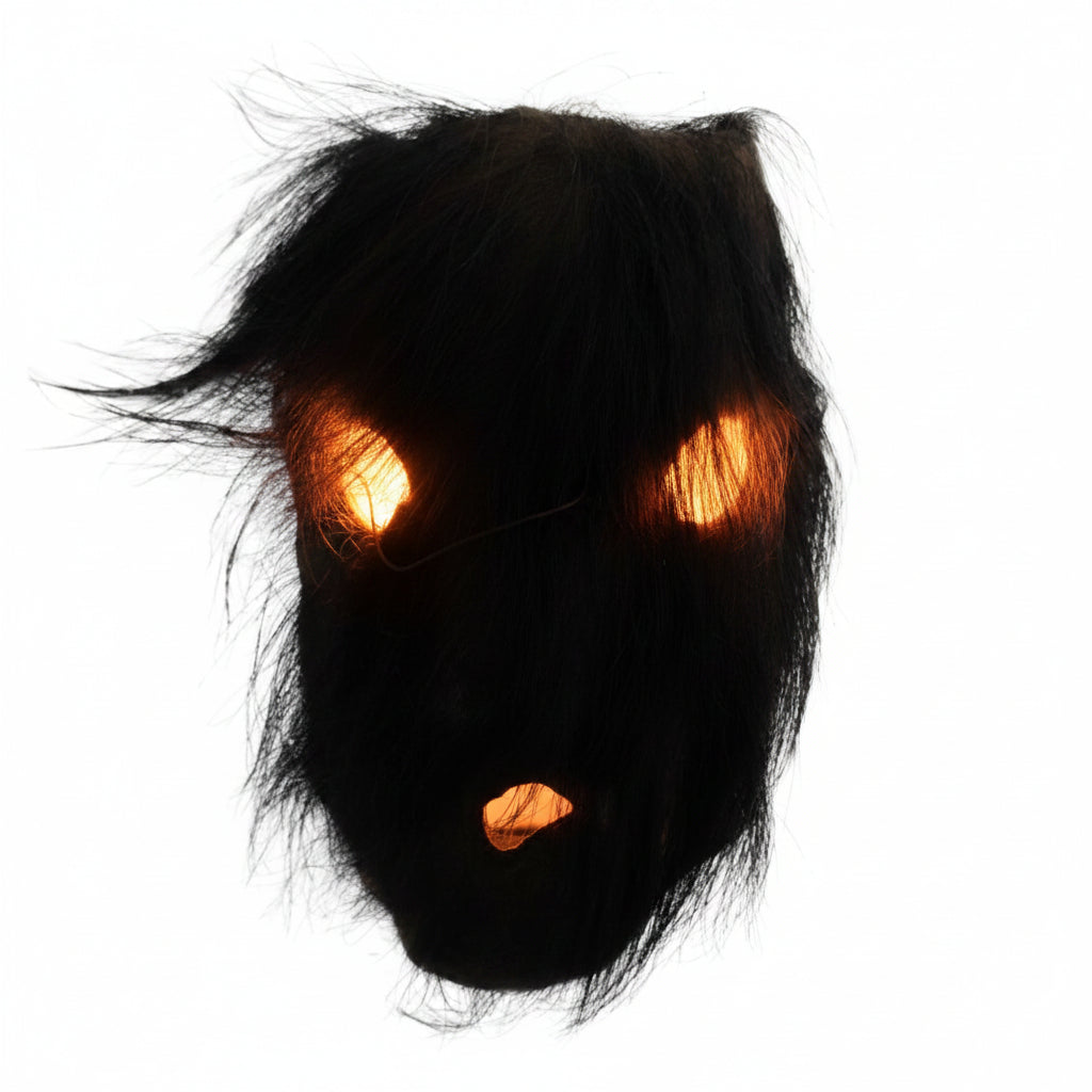Vue directe d'un masque rituel népalais dont les ouvertures pour les yeux et la bouche sont recouvertes d'une épaisse couche de poils de yak noirs biologiques.