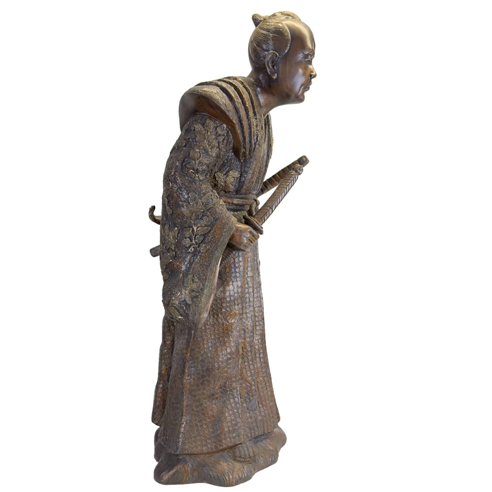 Close-up of the expressive face with an intense gaze and traditional chonmage hairstyle of the bronze Meiji Samurai.