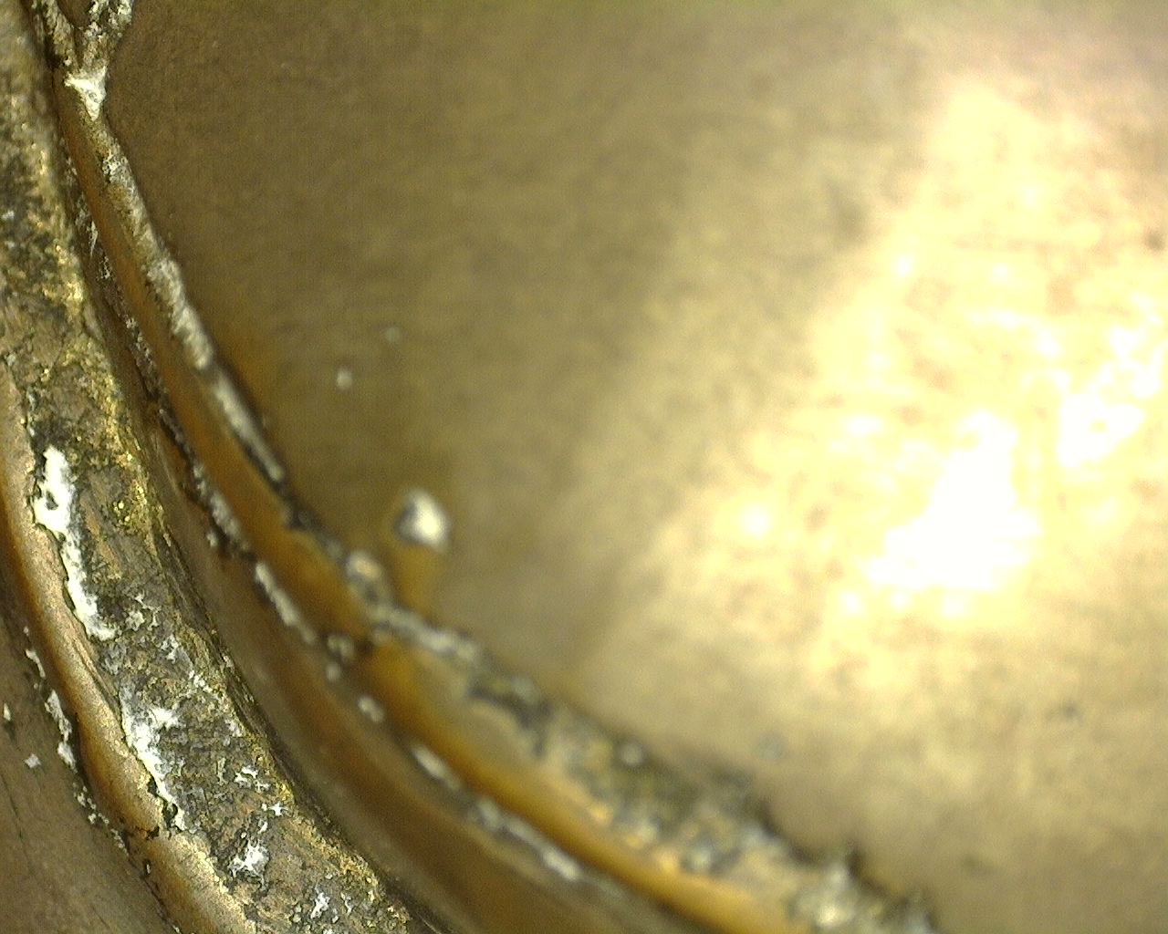 Close-up under raking light showing the natural aging, mineral residues, and authentic casting seams at the base of the Thai bronze.