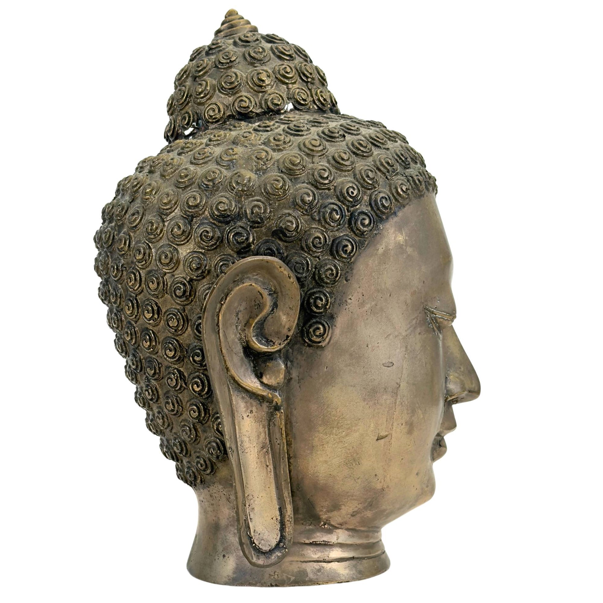 Three-quarter left view of the vintage brass-bronze Buddha head showing the elongated earlobes and the flowing facial profile.