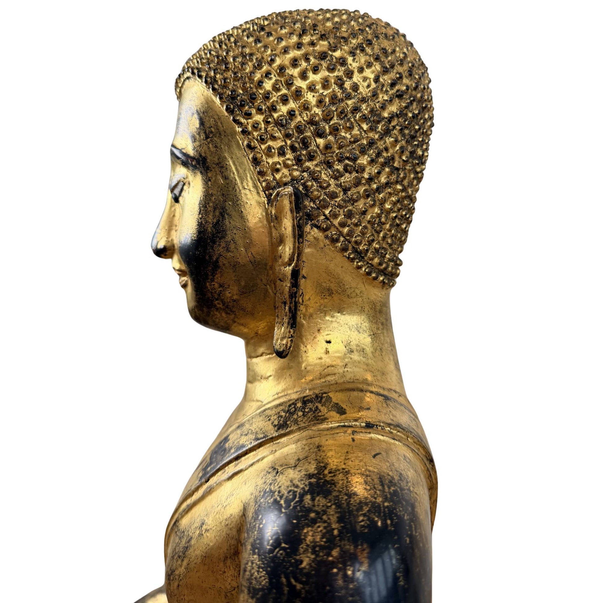 Facial detail of antique bronze Buddha with inlaid eyes, serene smile, and fire-gilded finish
