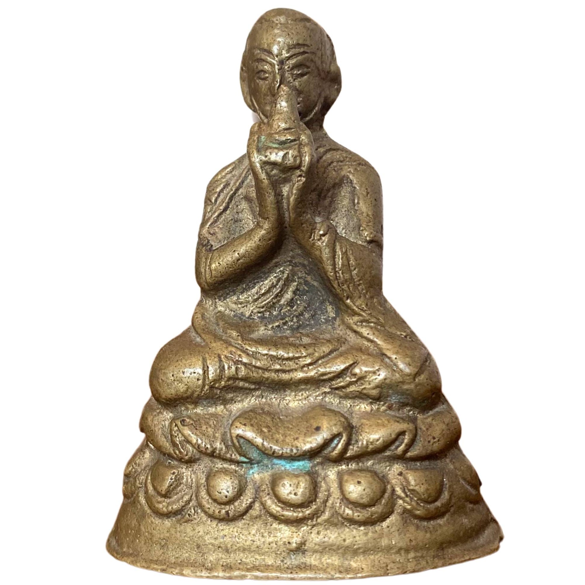 Front view of a seated Mahasiddha or Lama with a unique hand gesture at the mouth.
