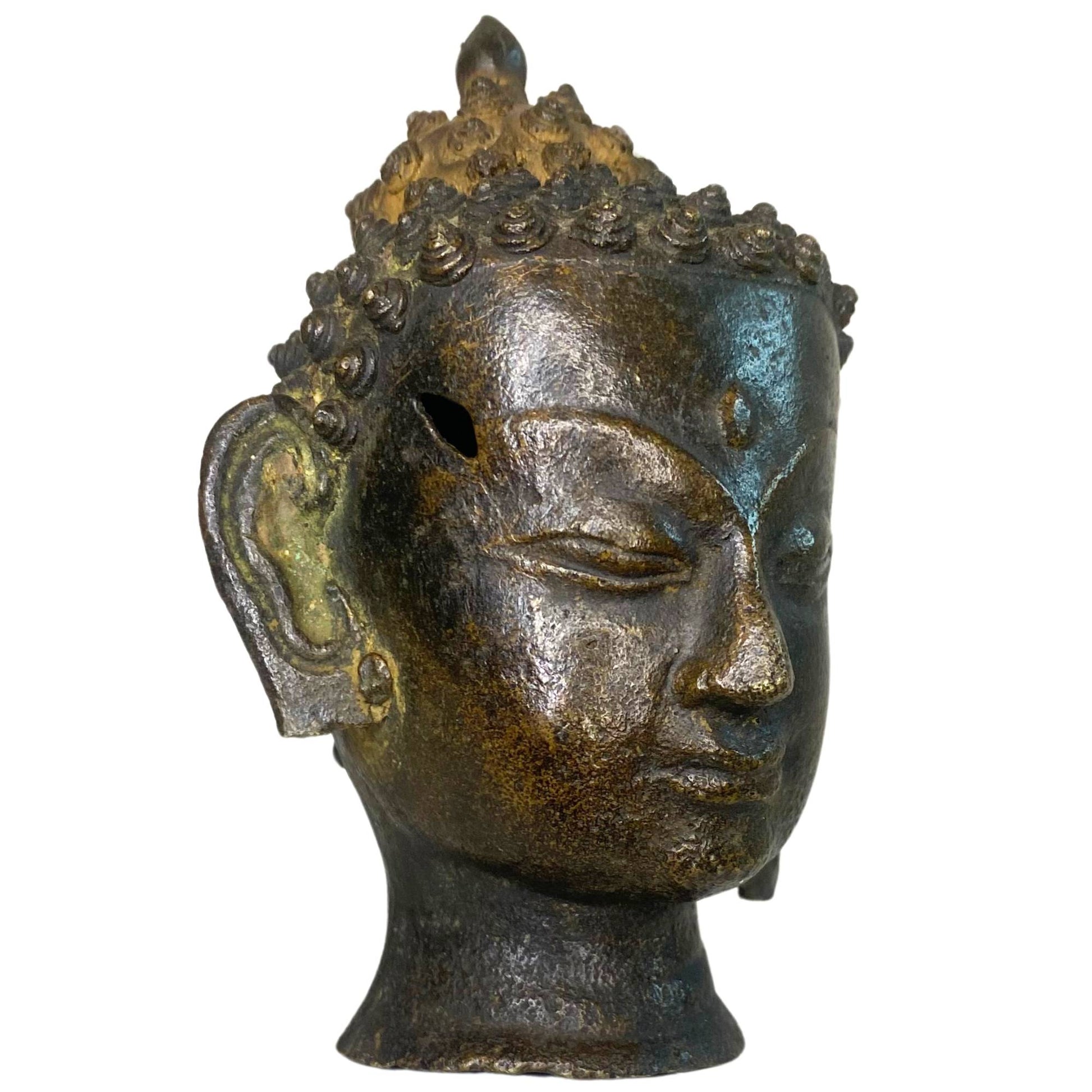 Right profile of the bronze Buddha head with a visible historical hole on the side.