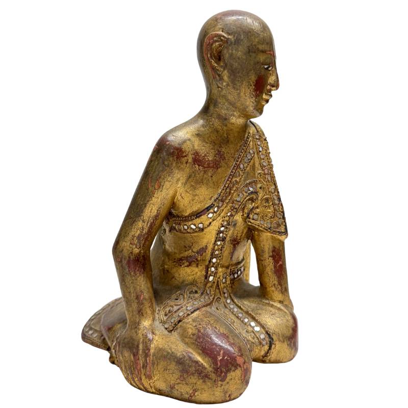Close-up of authentic gold leaf and red lacquer on an antique wooden statue.