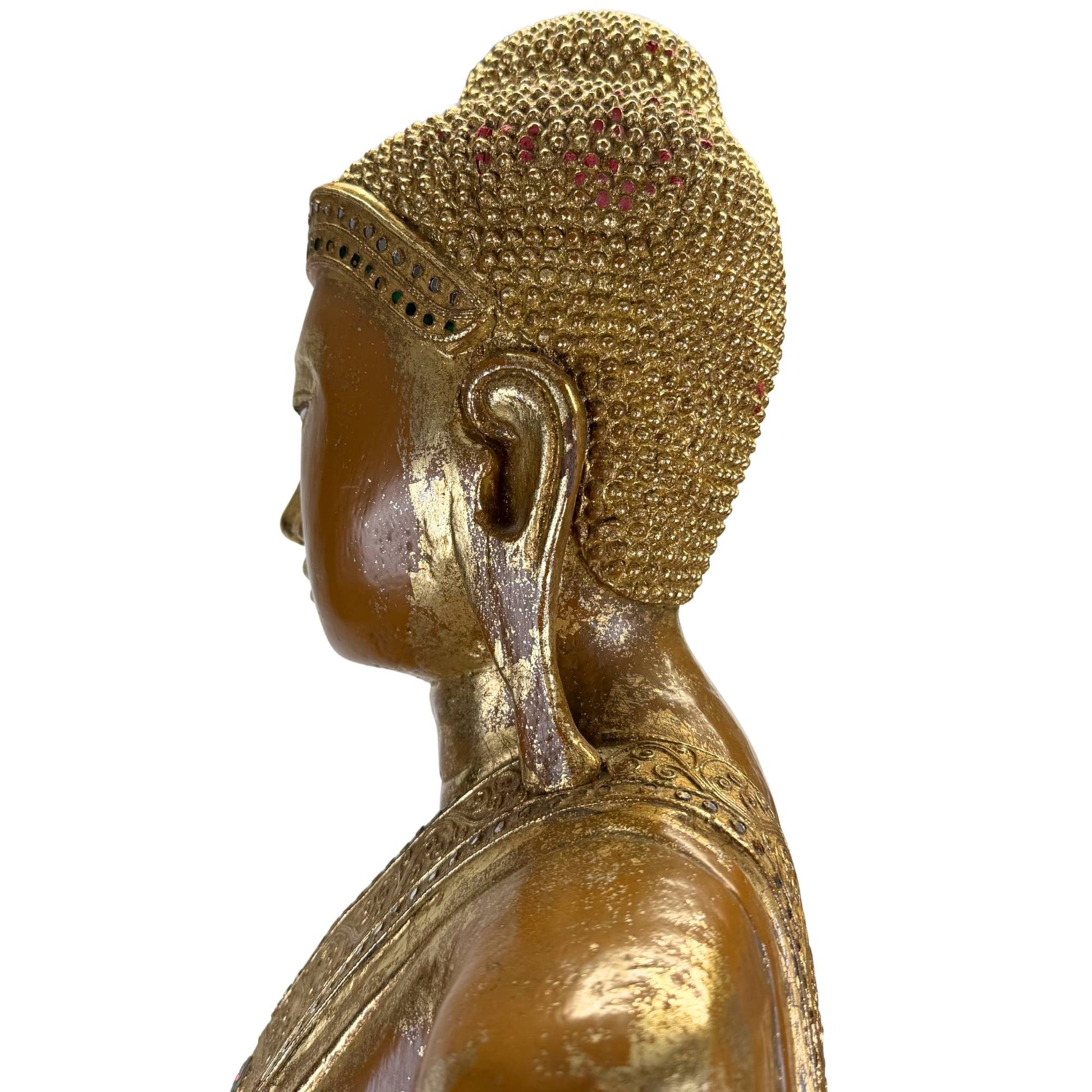 Detail of an antique Burmese Buddha with finely cut golden hair curls and remnants of red pigment.