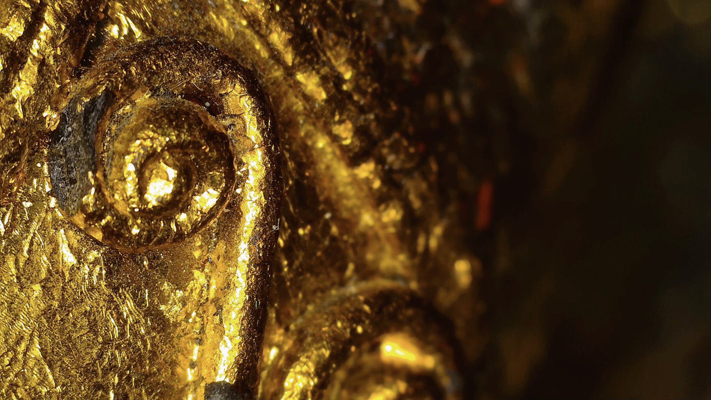 Microscope detail of gold leaf and relief decoration on the Burmese sculpture