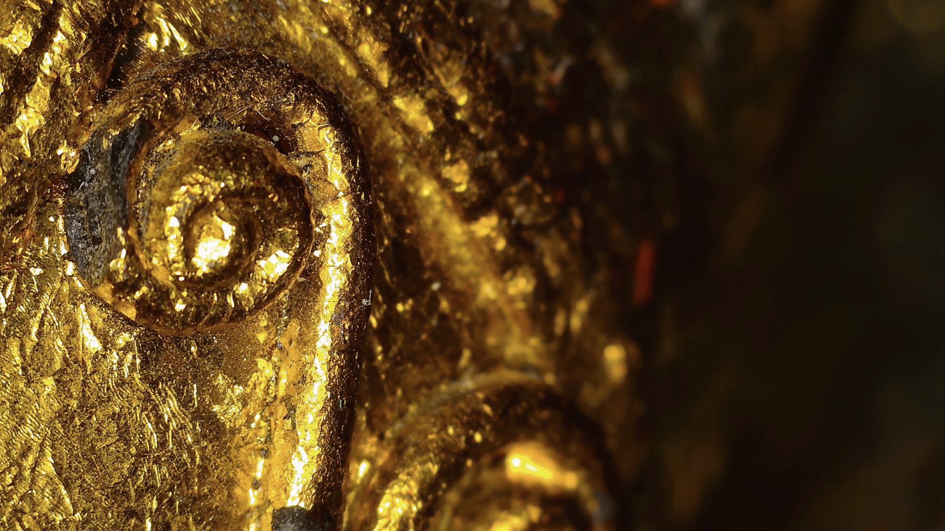 Microscope detail of gold leaf and relief decoration on the Burmese sculpture