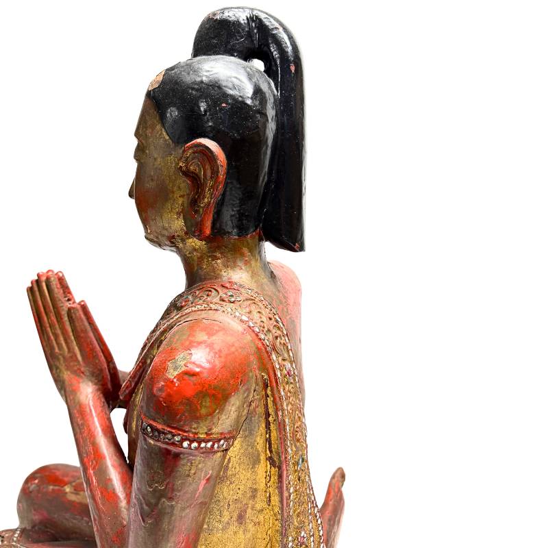 Burmese wooden statue in prayer posture with gold
