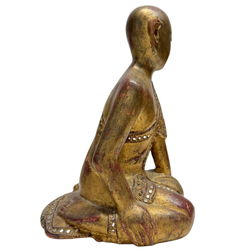 Side view of a kneeling Buddhist monk in a devotional posture.