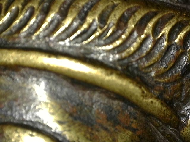 Microscope detail of fire gilding and wear on bronze Brahma statue