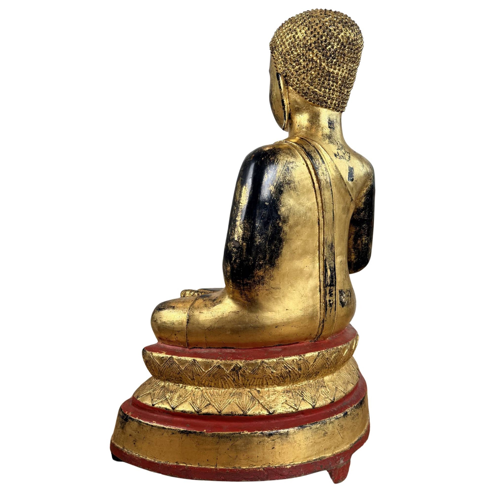 Bronze Buddha with fire gilding, red lacquer accents, black age-related wear, and a traditional spiritual appearance