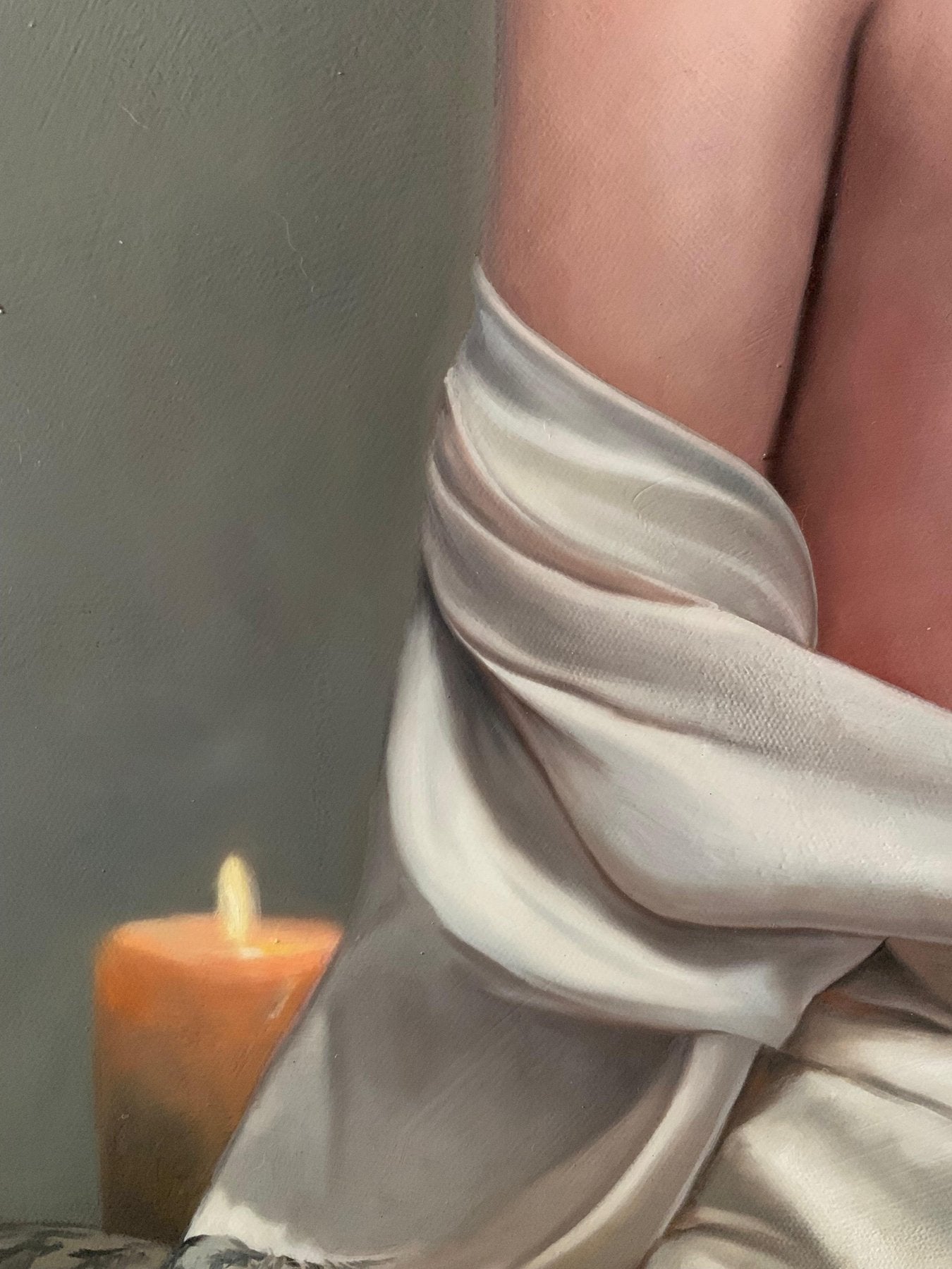 Close-up of the artist's handwritten black signature on the oil painting next to the warm glow of a painted candle.
