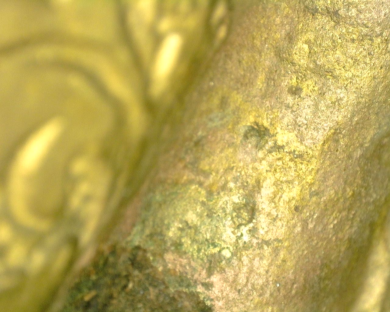 Close-up of the fire-gilded bronze surface with natural oxidation and wear.