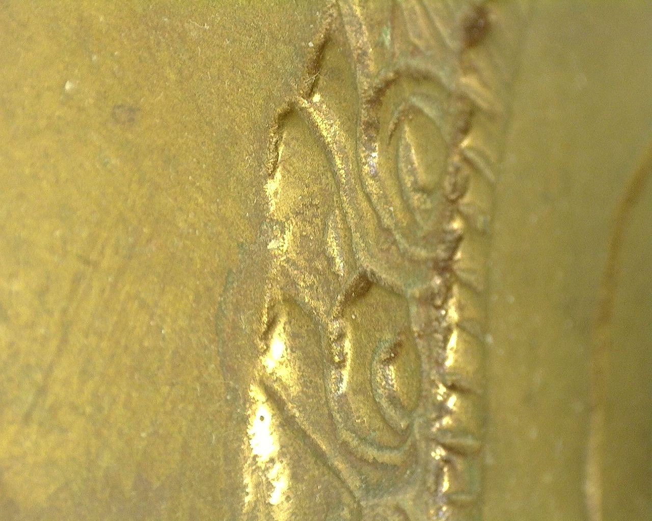 Microscopic image of the original fire gilding with natural wear and historical surface texture.