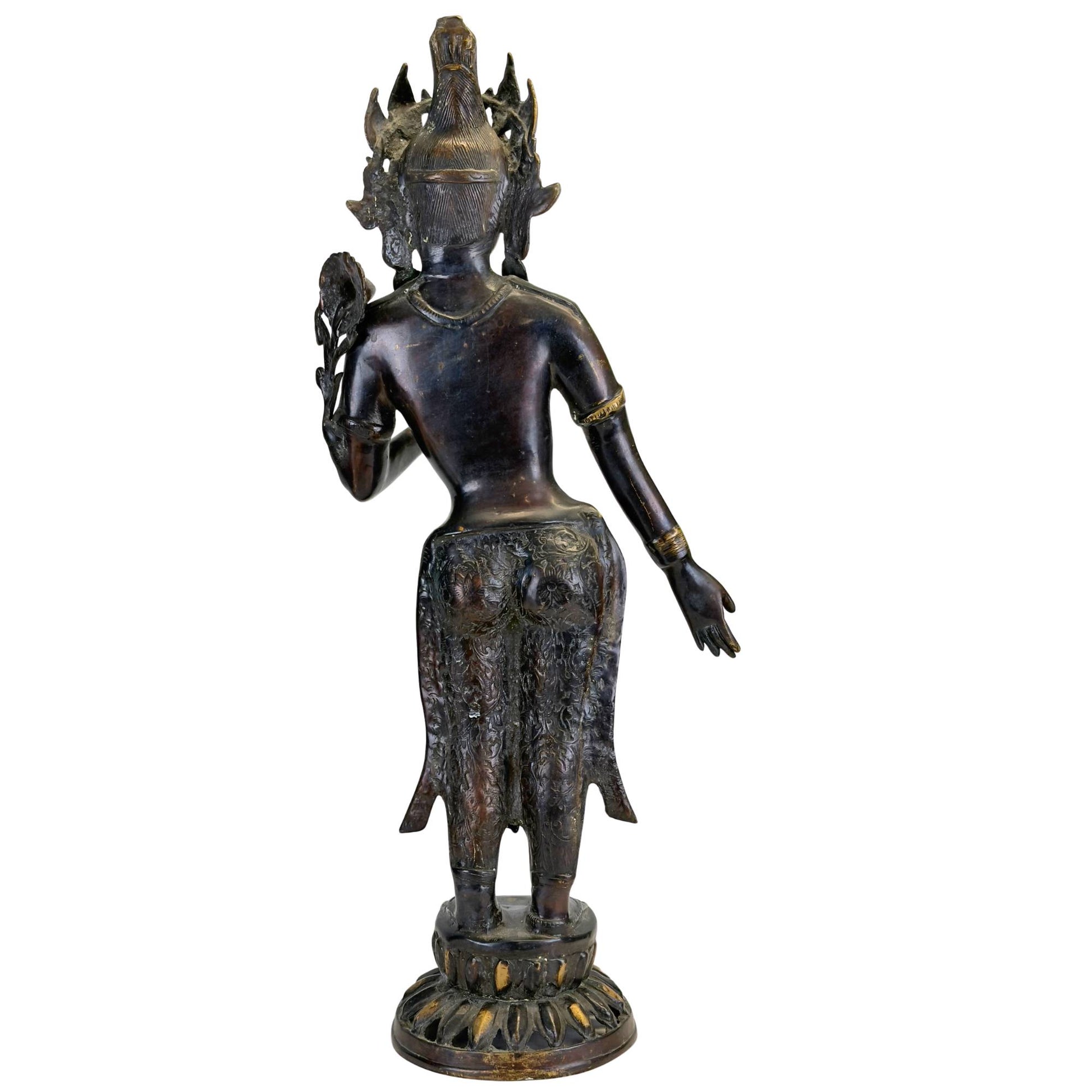 Left profile of an antique bronze Green Tara from Nepal with lotus stem, tribhanga posture, and black ritual patina.