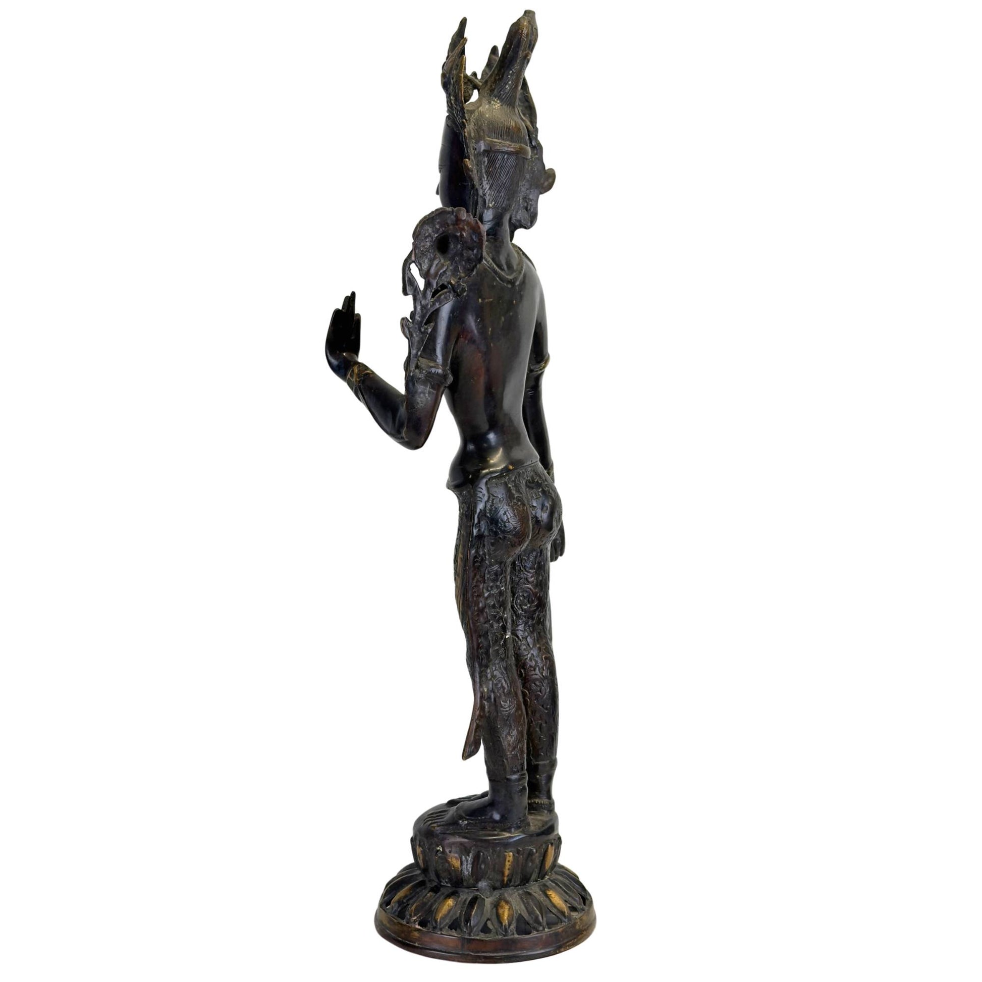 Oblique rear view of an antique bronze Green Tara from Nepal with openwork crown, lotus stem, black Newar patina, and fire-gilded accents.