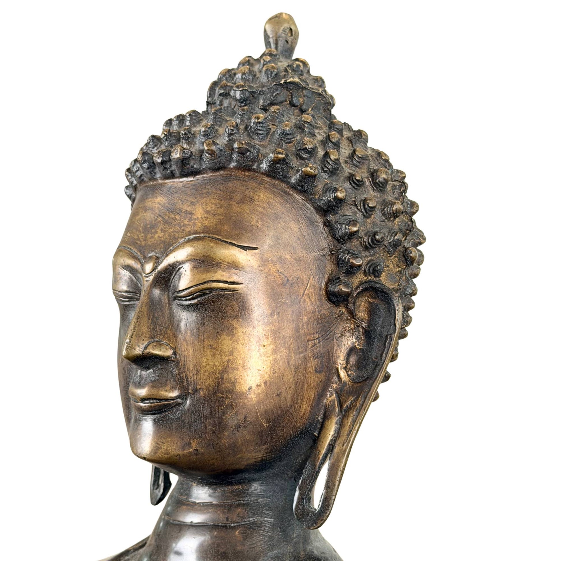 Serene facial expression of a Himalayan Buddha in fire-gilded bronze with dark patina and traditional design