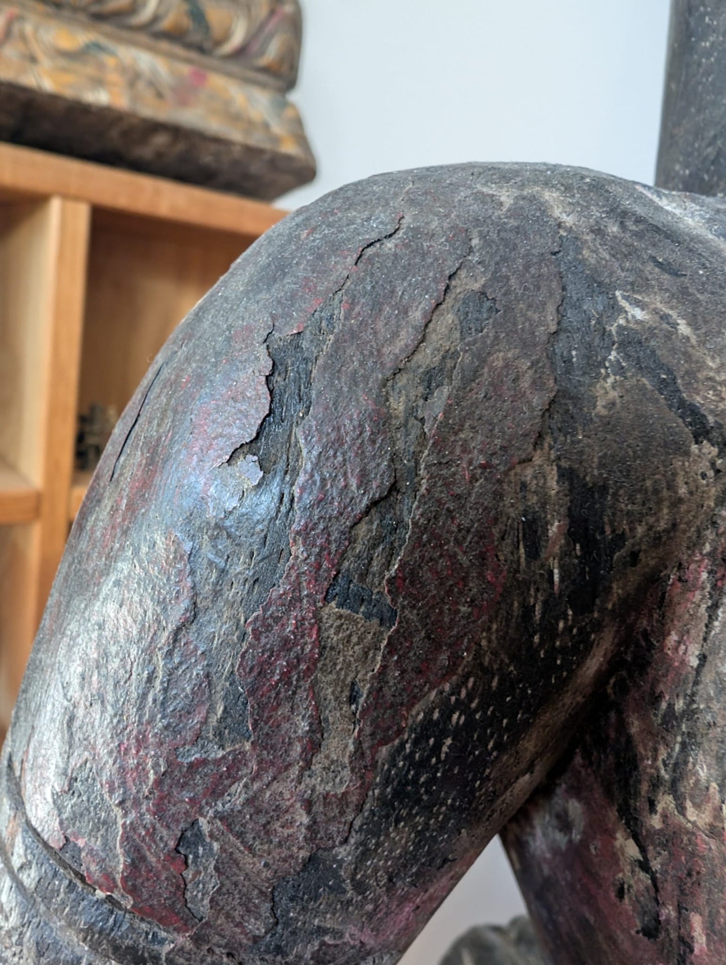 Detail of a wooden Lakshmi statue from Nepal with texture, patina, and crackle in the surface