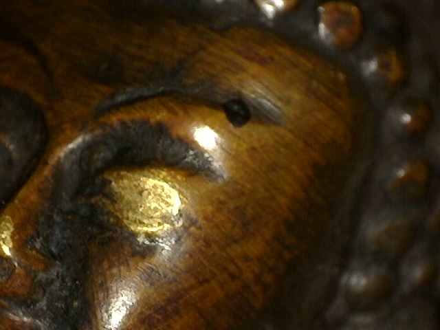 Microscope close-up of old fire gilding on a bronze Buddha with Dhyana Mudra