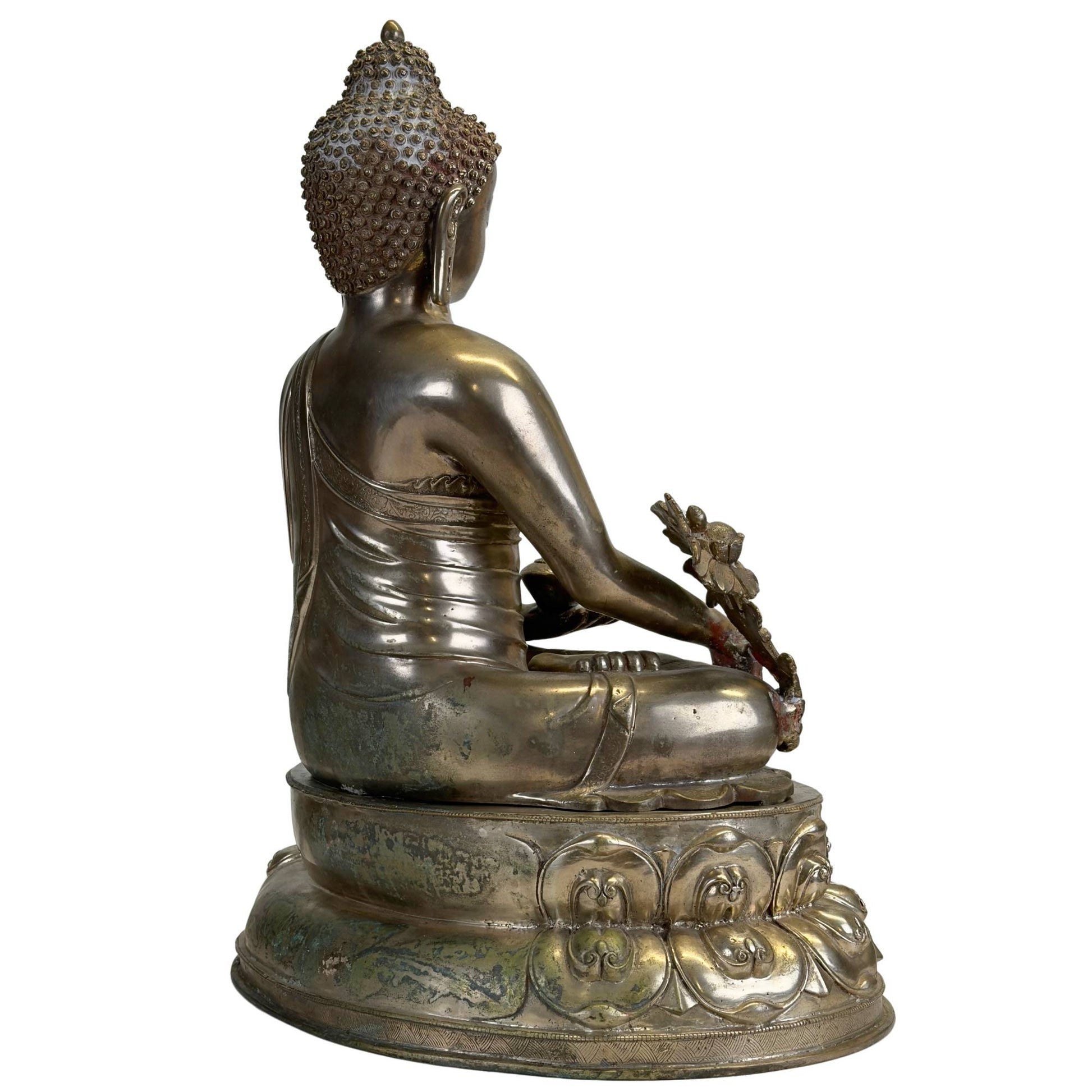 Three-quarter rear view of an antique Newar Bhaisajyaguru in silver-plated bronze with a richly chased robe, natural patina, and monumental double lotus throne.