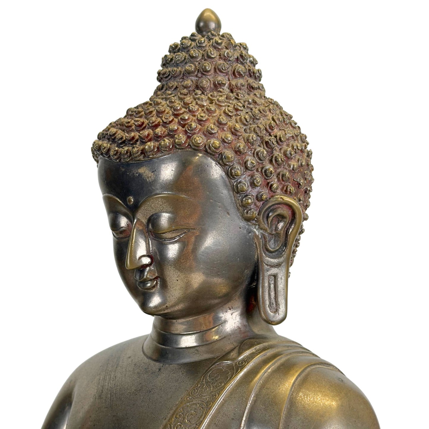 Oblique detail of the face of an antique Newar Bhaisajyaguru in silver-plated bronze with refined almond-shaped eyes, soft lips, long earlobes, characteristic hair curls, and natural wear consistent with a 14th–15th-century statue.