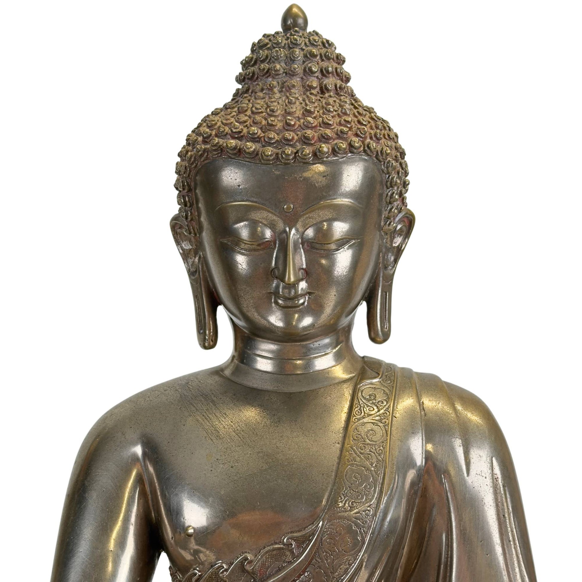 Detail of the face of an antique Newar Bhaisajyaguru in silver-plated bronze with a serene expression, almond-shaped eyes, finely modeled lips, urna, and characteristic hair curls with natural wear and patina.