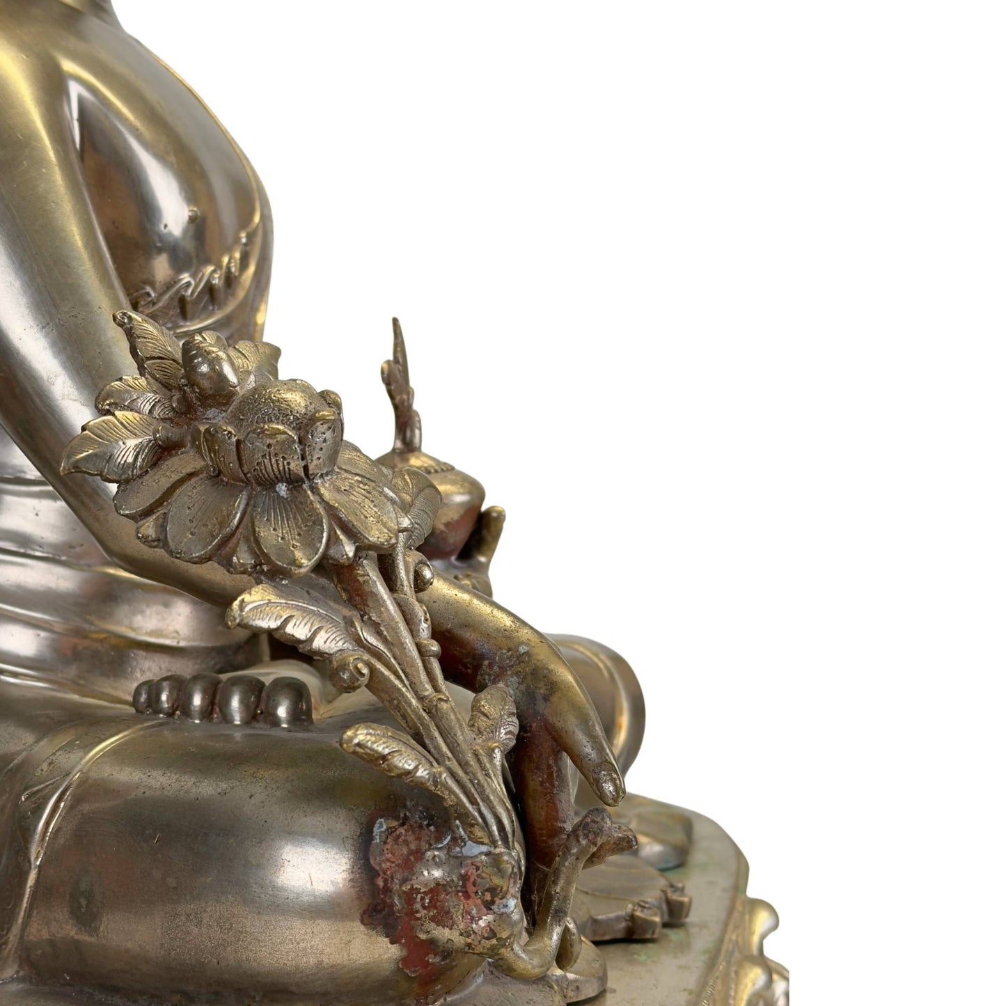 Detail of the richly detailed utpala lotus and medicinal plant of an antique Newar Bhaisajyaguru in silver-plated bronze, with original signs of ritual use and natural patina.
