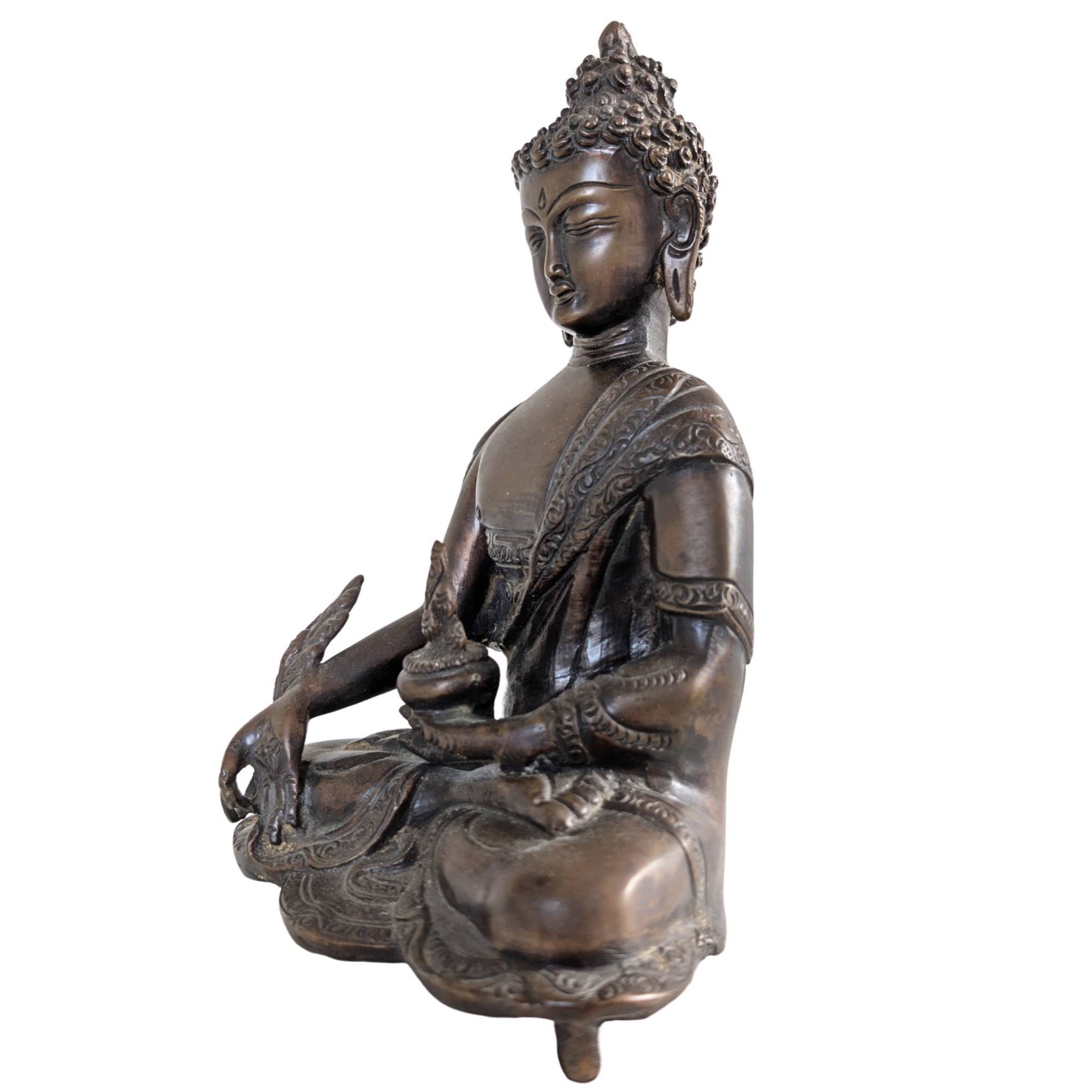 Profile of the Medicine Buddha sculpture with emphasis on the deep patina.
