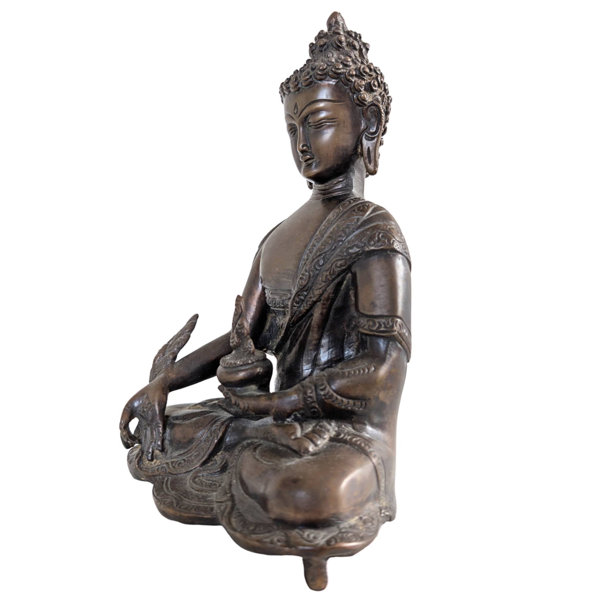 Profile of the Medicine Buddha sculpture with emphasis on the deep patina.