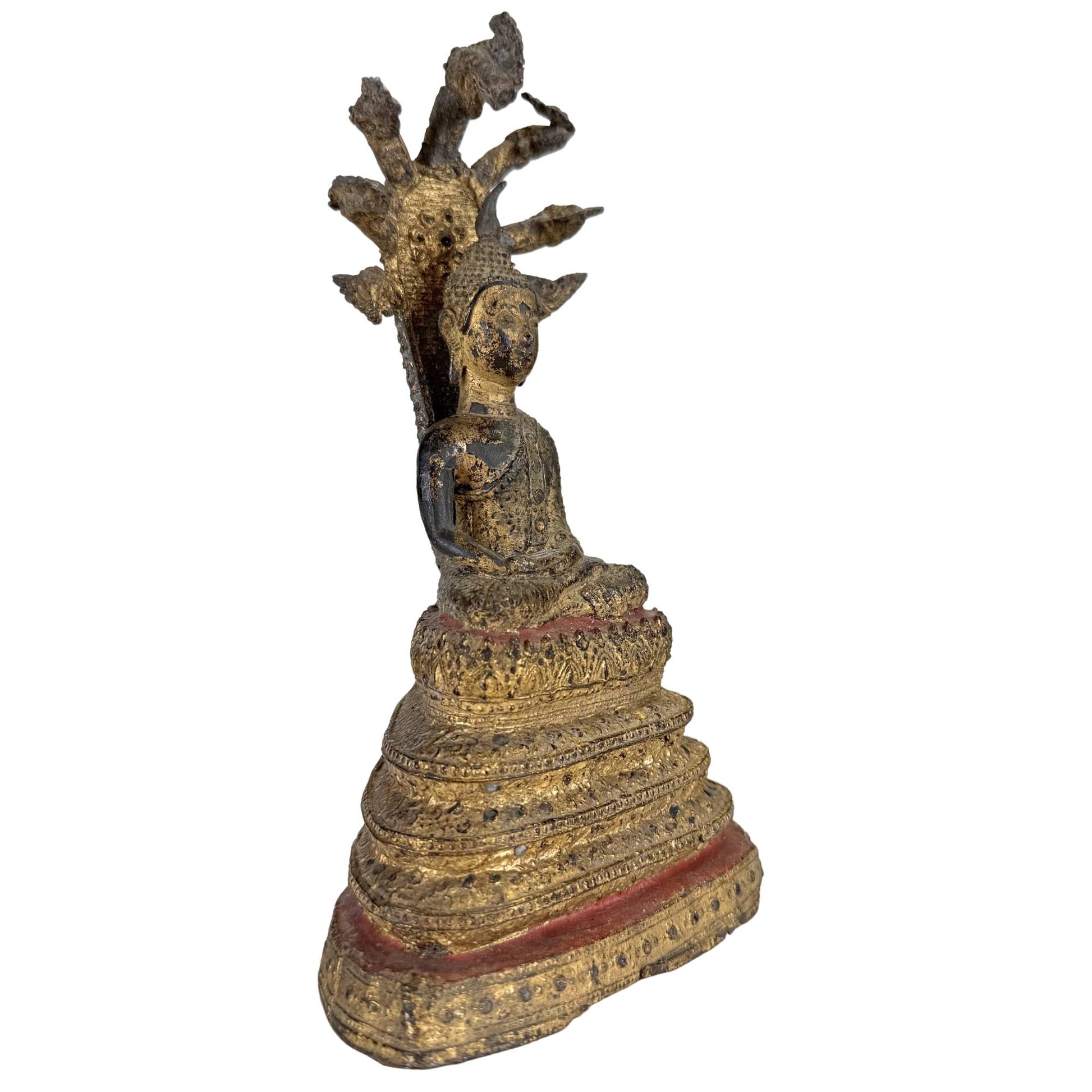 Side view of antique Thai Naga Buddha with gilded finish and multi-headed snake