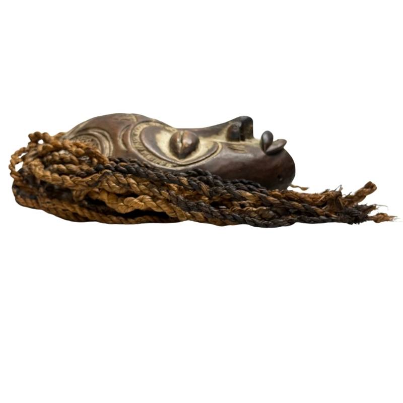 Tribal African mask with carved spiral motifs, hand-carved wood, and expressive white-painted face