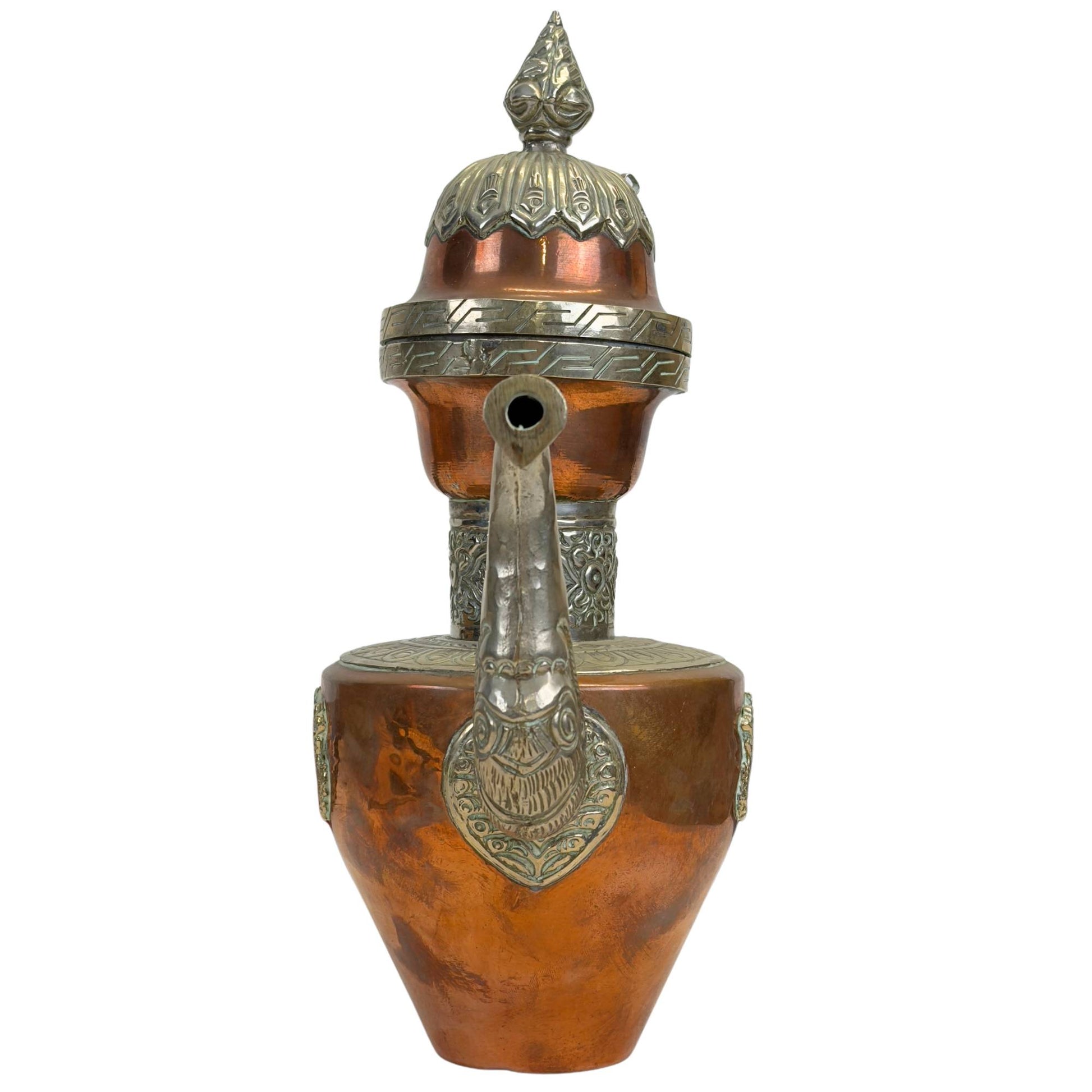 Direct vooraanzicht van de schenktuit met de florale en mythologische paktong reliëfelementen aan de basis van de tuit.
