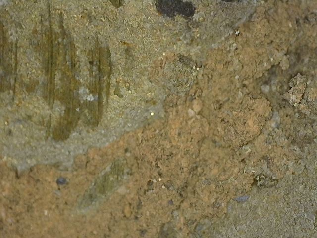 Microscopic image of gold leaf fragments between layers of cuprite on a Khmer bronze Vishnu bust