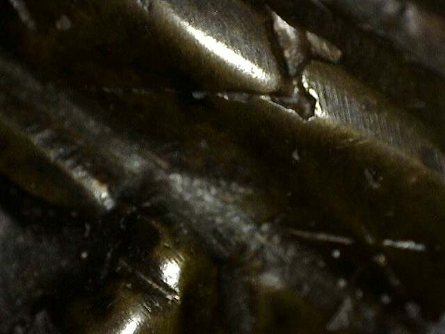 Detail of fragmentary gold leaf remnants embedded in patina on a Khmer bronze Vishnu bust