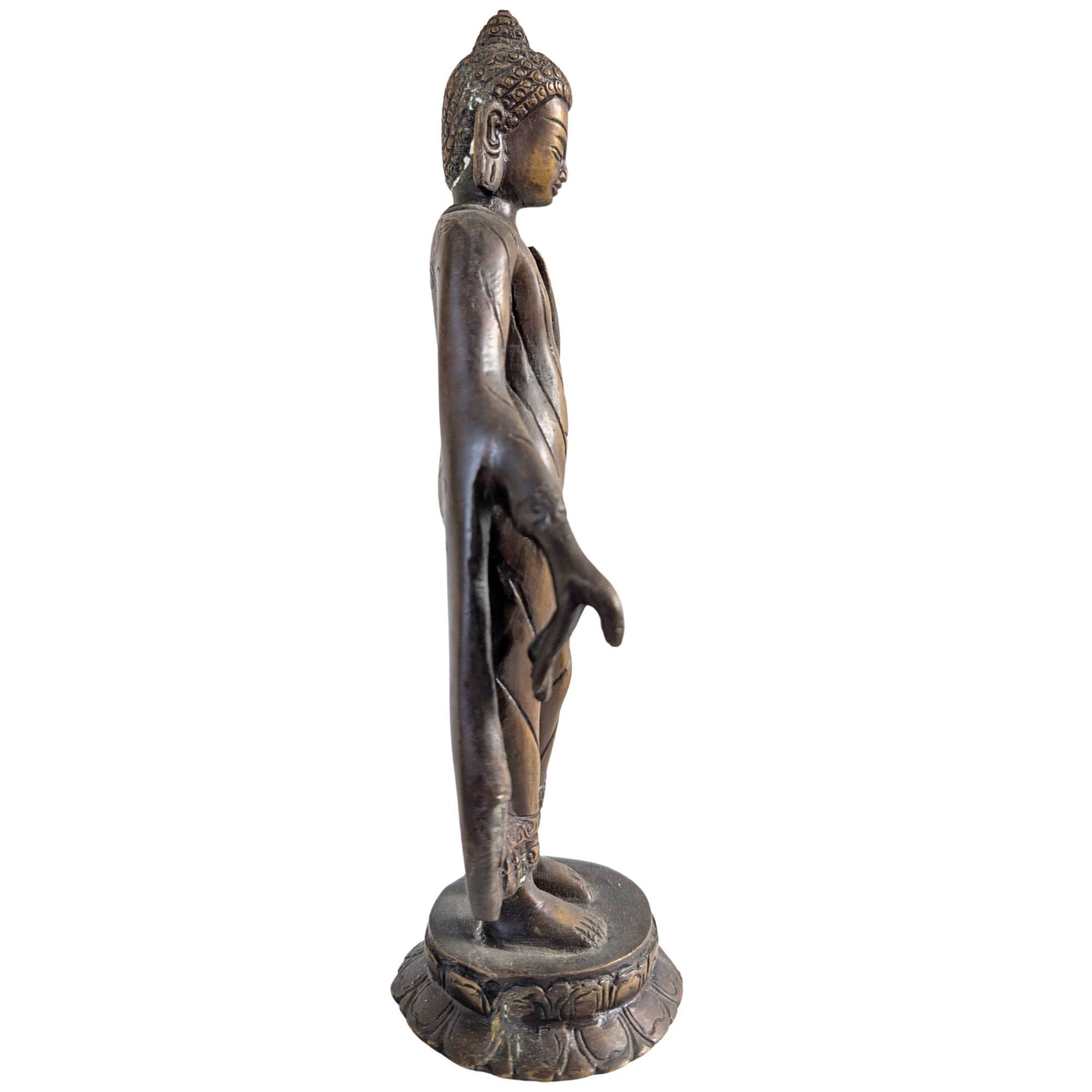Side view of the standing Buddha figure with flowing robes in bronze.